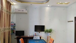 A room with a pool table, two chairs, a television, a plant, and a coat rack. - qinggangxian yinzuo shishangbinguan (Qinggang)