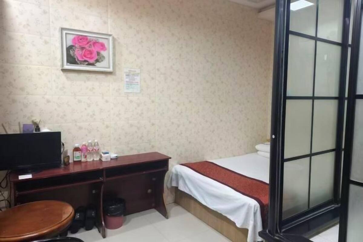 Ein Zimmer mit einem Bett, einem Schreibtisch mit Computer, einem Stuhl und einem Fernseher.