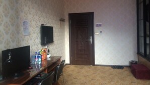 A room with a desk, computer, and a TV. There is a door, a window, and a patterned carpet. - qinggangxian yinzuo shishangbinguan (Qinggang)