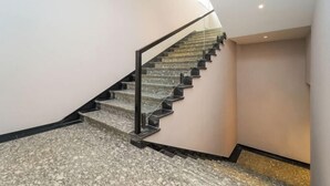 Een trap met een zwarte metalen leuning en een marmeren vloer.