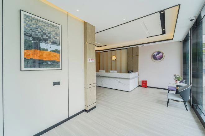 A modern reception area with a marble counter, a framed artwork, and a small seating area with a plant.