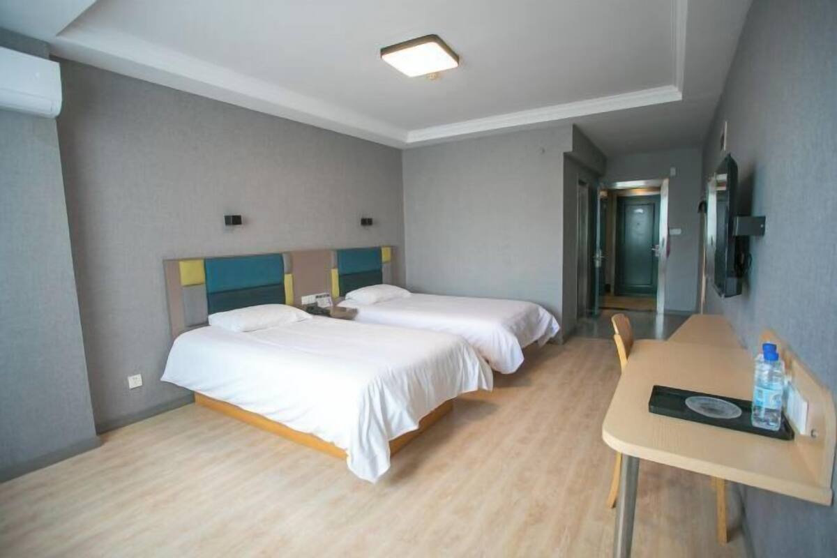 A hotel room with two beds, a desk, and a chair.