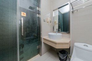 A bathroom with a glass shower enclosure, a white sink, a mirror, and a toilet. - Xinrenren hotel (Shanghai)