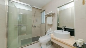 A bathroom with a glass shower enclosure, a toilet, a sink, and a mirror. - Xinrenren hotel (Shanghai)