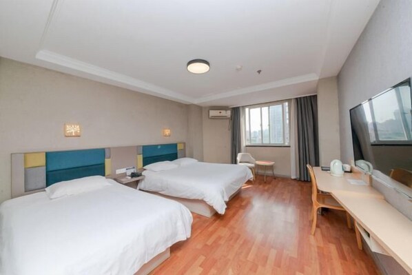 A hotel room with two beds, a desk, a chair, a TV, and a window with curtains.