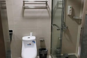 A bathroom with a toilet, a glass shower enclosure, and a trash bin. - Xinrenren hotel (Shanghai)