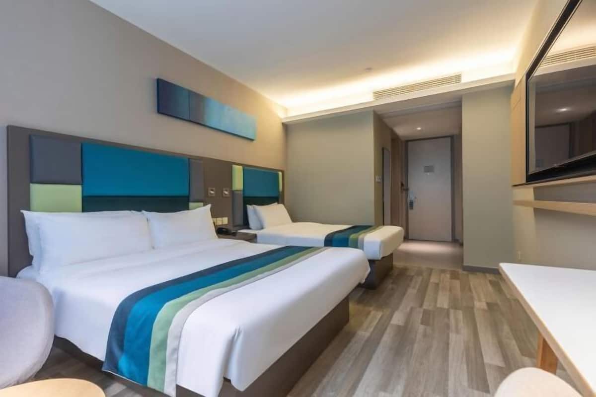 A hotel room with two beds, a desk, and a TV.