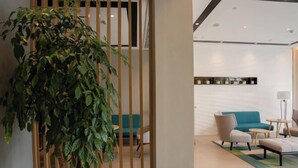 A modern hotel lobby with a large potted plant, a teal sofa, and a small round table. - Homeinn Selected Hotel (Chuzhou Mingguang Mingzhu Avenue Zhengyuan Plaza) (Mingguang)