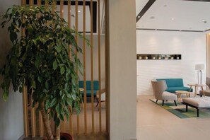 A modern hotel lobby with a large potted plant, a teal sofa, and a small round table. - Homeinn Selected Hotel (Chuzhou Mingguang Mingzhu Avenue Zhengyuan Plaza) (Mingguang)