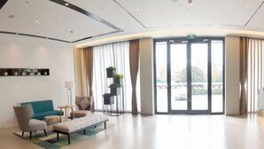 A modern hotel lobby with a curved reception desk, seating area with sofas and chairs, a small table, and a large glass door leading outside. - Homeinn Selected Hotel (Chuzhou Mingguang Mingzhu Avenue Zhengyuan Plaza) (Mingguang)