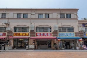 A multi-story building with several storefronts, including a restaurant, a convenience store, and a shop with a blue sign.