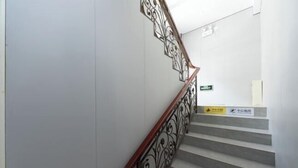A staircase with a wooden handrail and decorative metal balusters. - Ruihe Hostel (Shanghai)