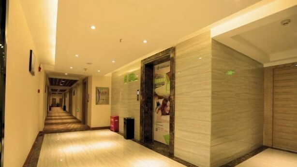 A hotel corridor with a polished floor, marble walls, and a framed picture on the left. - Morning Inn Hotel (Yanling County Government) (Yanling)