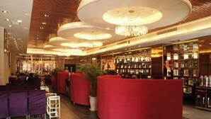 A modern hotel lobby with a central reception desk, seating areas, and a well-lit ceiling with chandeliers. - Sijiwenhua Hotel (Feicheng)
