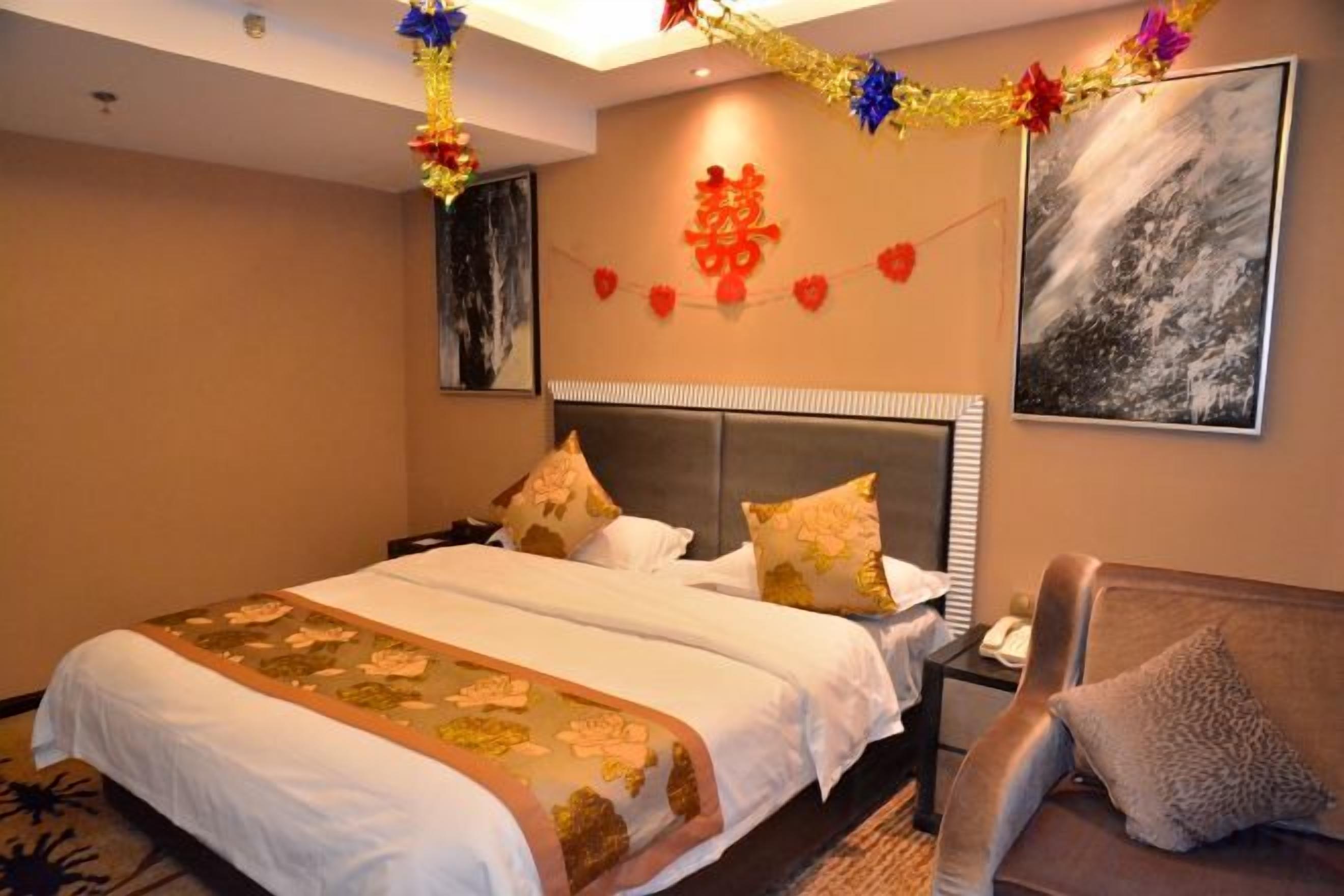 A hotel room with a large bed, a nightstand, a sofa, and a wall-mounted TV.