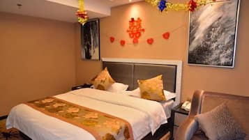 A hotel room with a large bed, a nightstand, a sofa, and a wall-mounted TV.