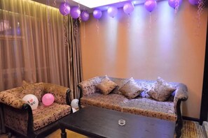 A room with a sofa and a table, curtains, and balloons. - Sijiwenhua Hotel (Feicheng)