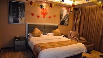 A hotel room with a large bed, a chair, a nightstand, and artwork on the walls.