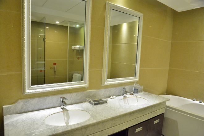 A bathroom with two sinks, a bathtub, and two large mirrors.