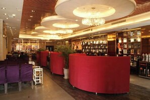 A modern hotel lobby with red seating, a bar area, and a large chandelier. - Sijiwenhua Hotel (Feicheng)