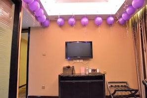 Una stanza con televisione a parete, una scrivania della reception e una finestra con tende.
