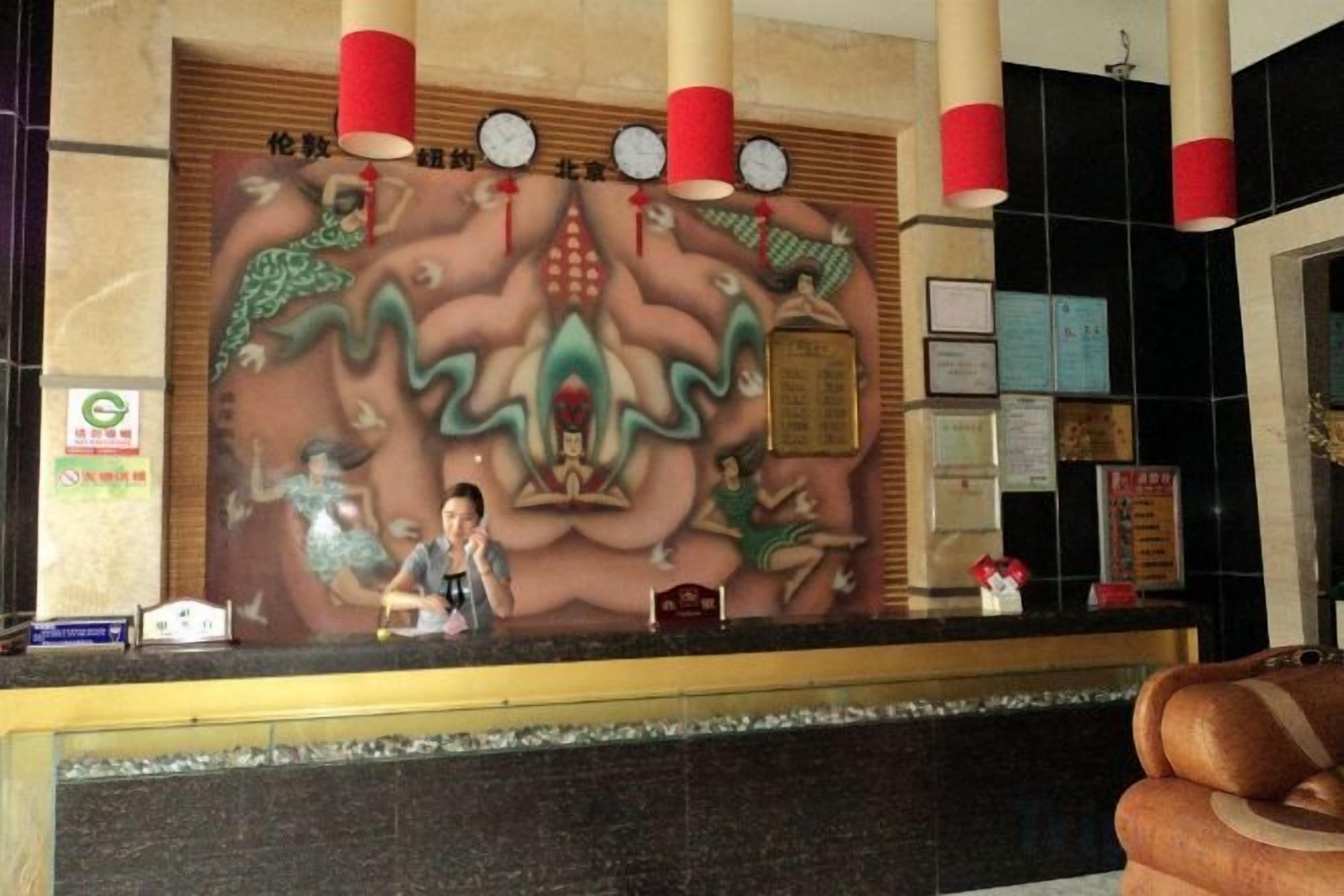 Una taquilla de recepció amb un mural decoratiu, un rellotge i un tabló d'anuncis.