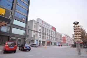 A multi-story building with a commercial ground floor, a parking lot, and a distinctive spherical structure on the right. - Sijiwenhua Hotel (Feicheng)