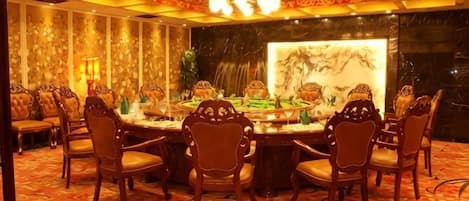 A banquet hall with a round table, chairs, and a decorative fountain.