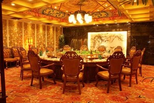A banquet hall with a round table, chairs, and a decorative fountain.