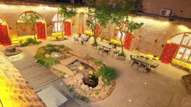 An outdoor courtyard with stone walls, seating areas, and a small water feature.