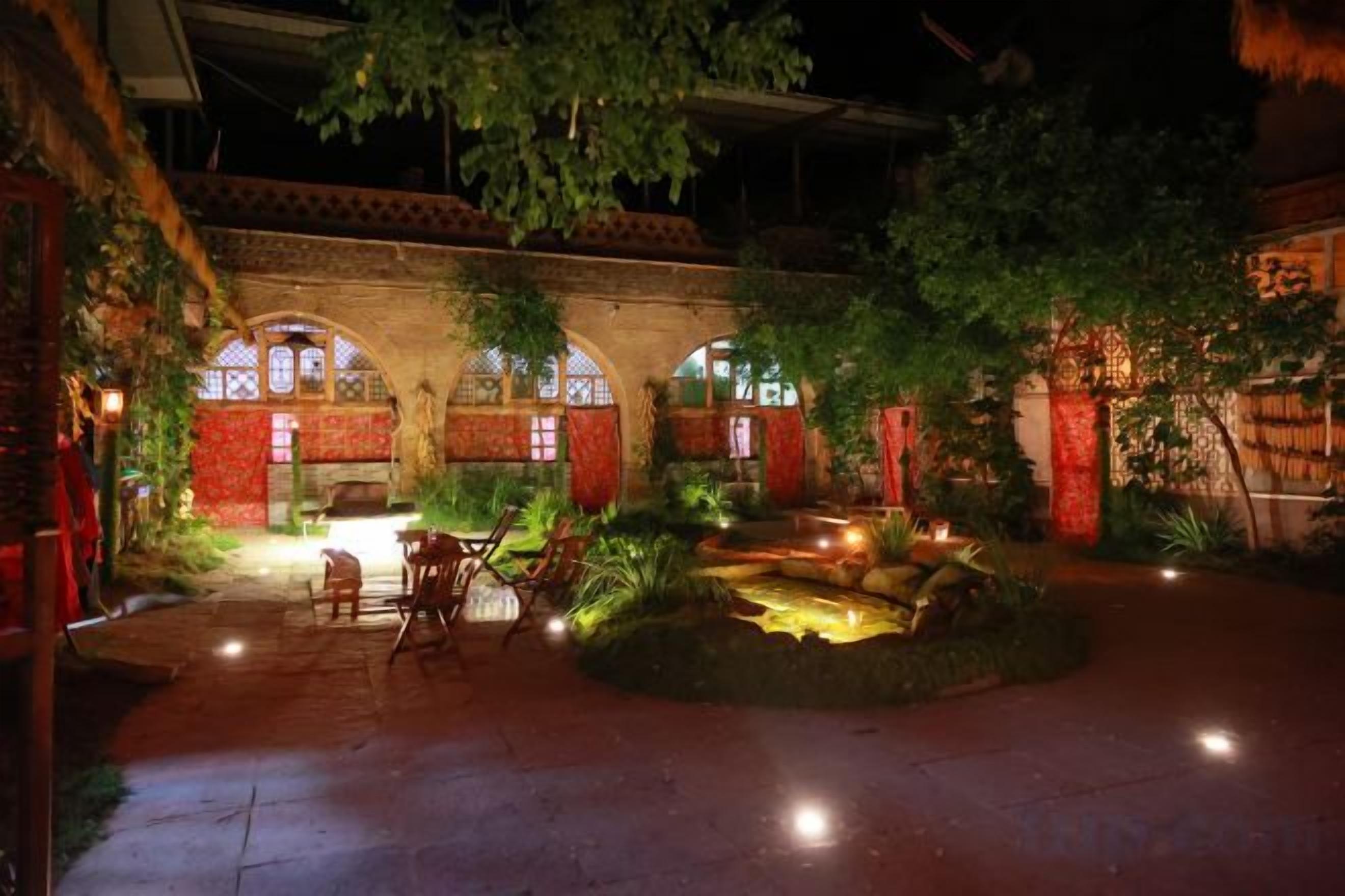 An outdoor courtyard with a brick archway, seating area, and a small water feature.