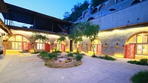 A courtyard with stone flooring, arched doorways, and a small water feature.