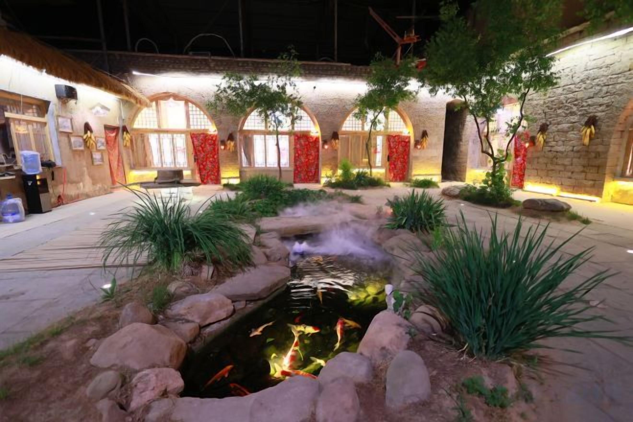 Un patio exterior con un estanque, paredes de piedra y plantas.
