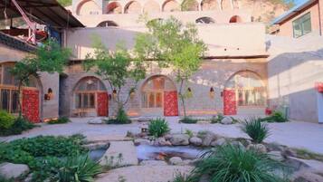 A courtyard with a stone building, arched doorways, and a small water feature.