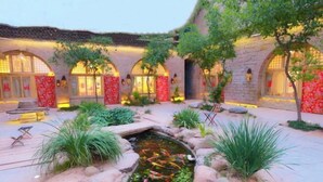 A courtyard with a koi pond, stone walls, and traditional Chinese architecture.