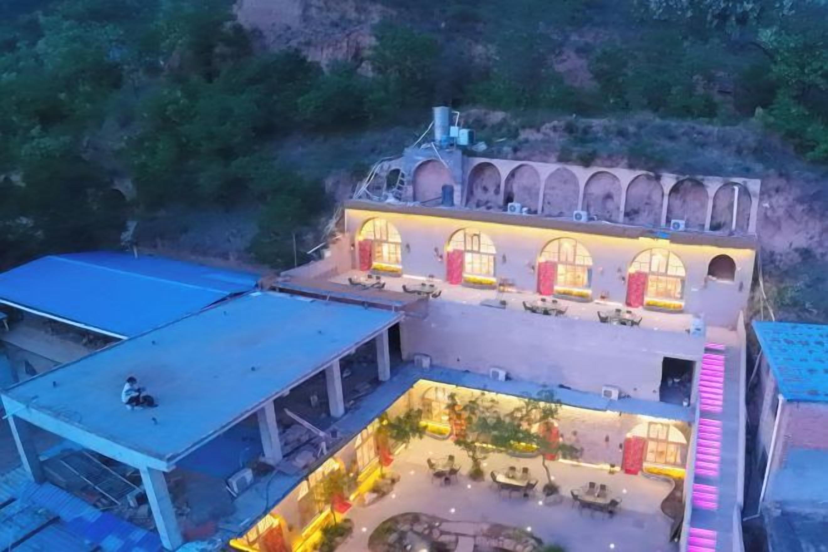 Un hôtel doté d’une cour intérieure, de nombreuses arcades et d’un espace extérieur aménagé avec des sièges, protégé par un toit.