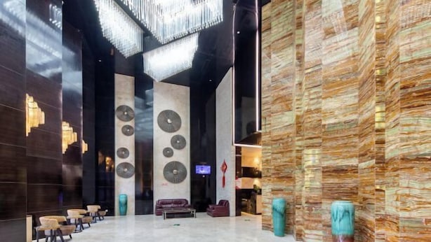 A spacious lobby with a modern design, featuring a central seating area, a large chandelier, and a unique textured wall on the right. - Yunlong Hotel (Wenling Yintai Branch) (Wenling)