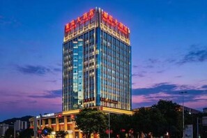 A tall, modern building with a glass facade and illuminated signage at the top. - Yunlong Hotel (Wenling Yintai Branch) (Wenling)