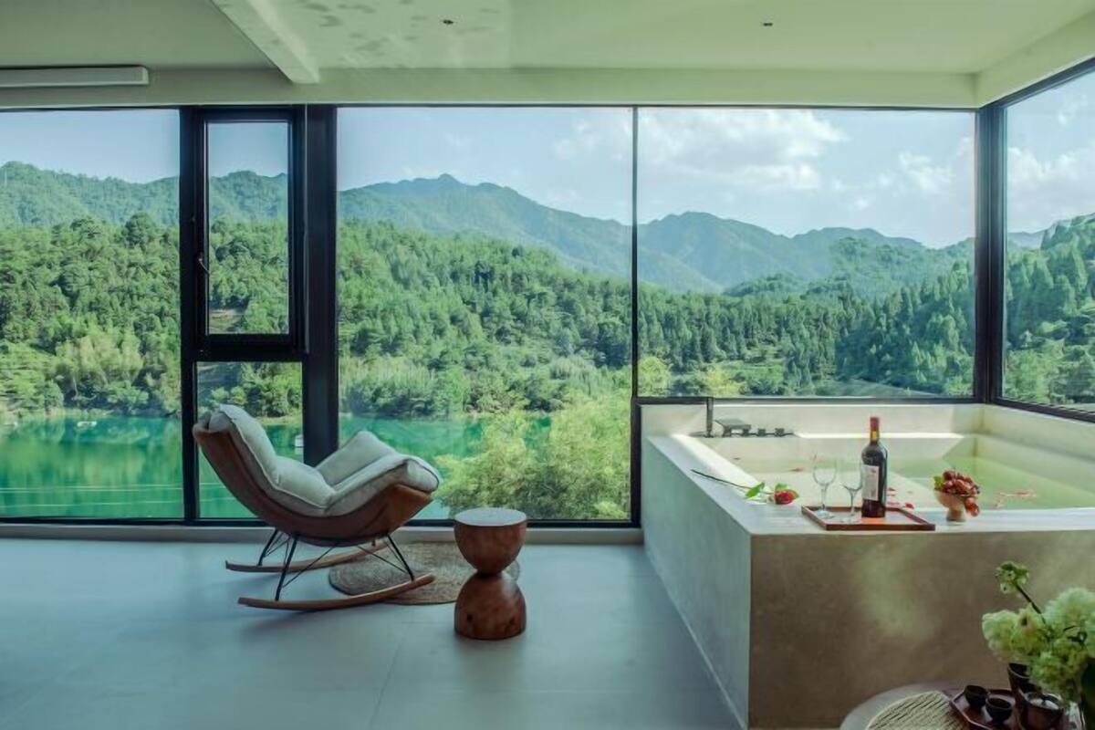 A modern room with a large window, a bathtub, and a rocking chair.