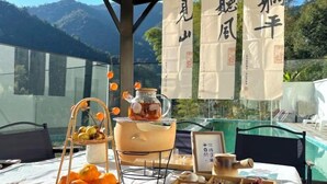 A table set with food and a teapot, with a mountain view in the background. - Hi Ta B&B (Chun'an)