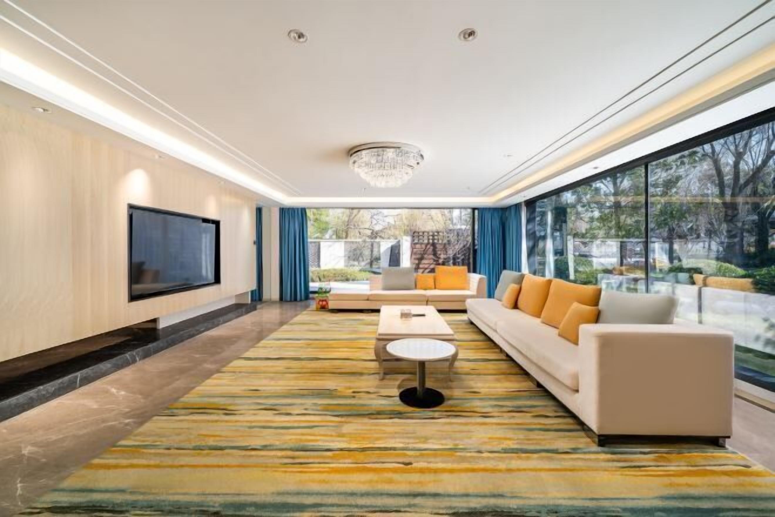 A modern living room with a large TV, sofa, coffee table, and a patterned rug.