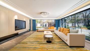 A modern living room with a large TV, sofa, coffee table, and a patterned rug.