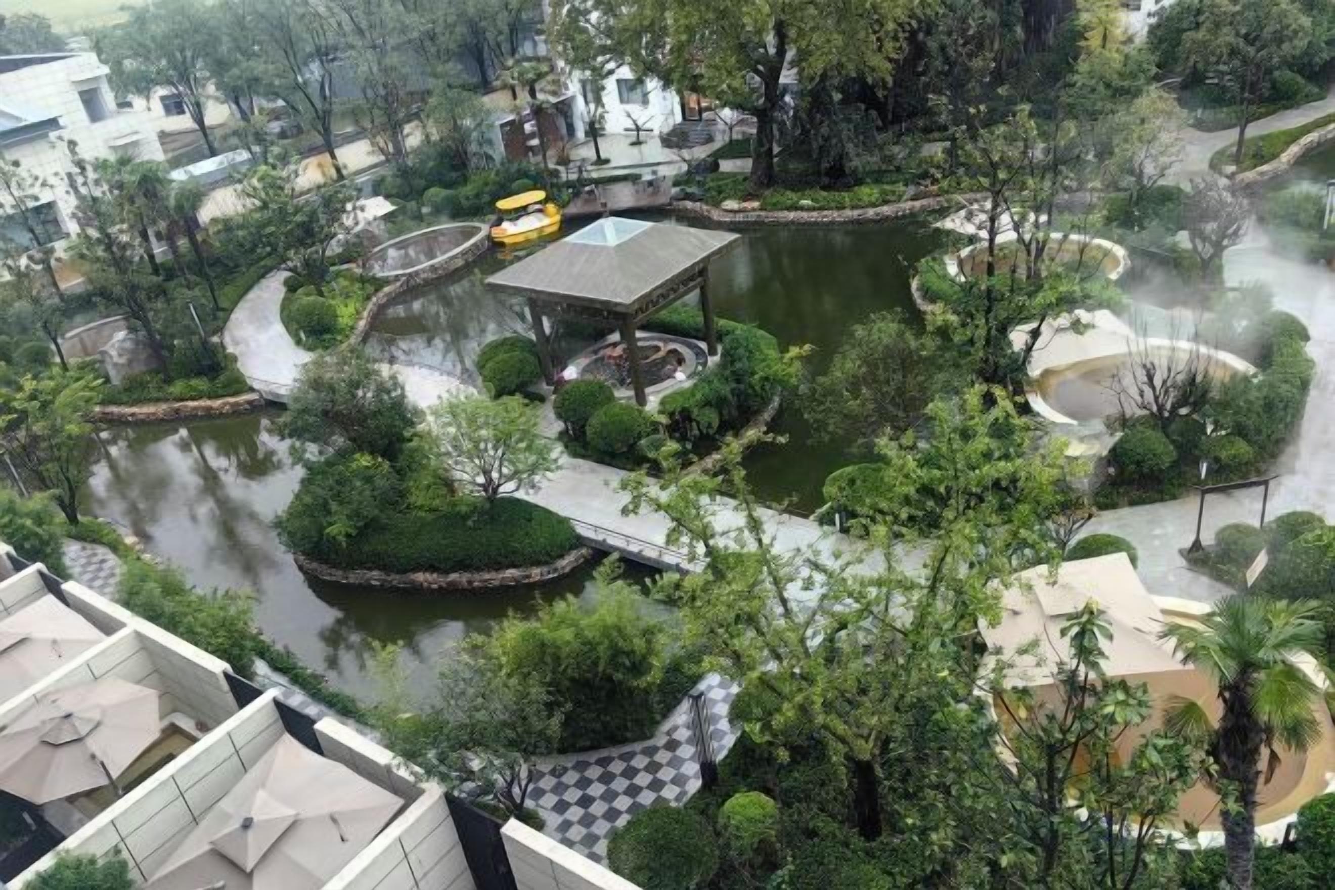 Ein angelegter Garten mit Teich, Wegen und einem Pavillon.