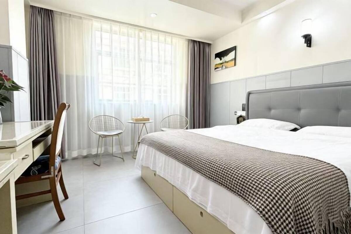 Habitación de hotel con cama, escritorio, dos sillas, una mesita y un cuadro en la pared.