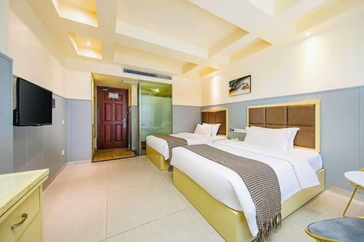 Habitación de hotel con dos camas, televisión, escritorio y una silla.
