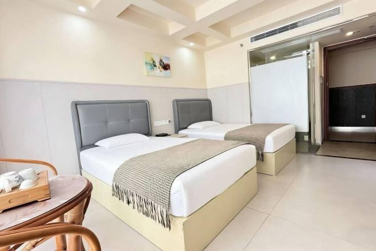 Una habitación de hotel con dos camas, una mesa de comedor y una kitchenette.