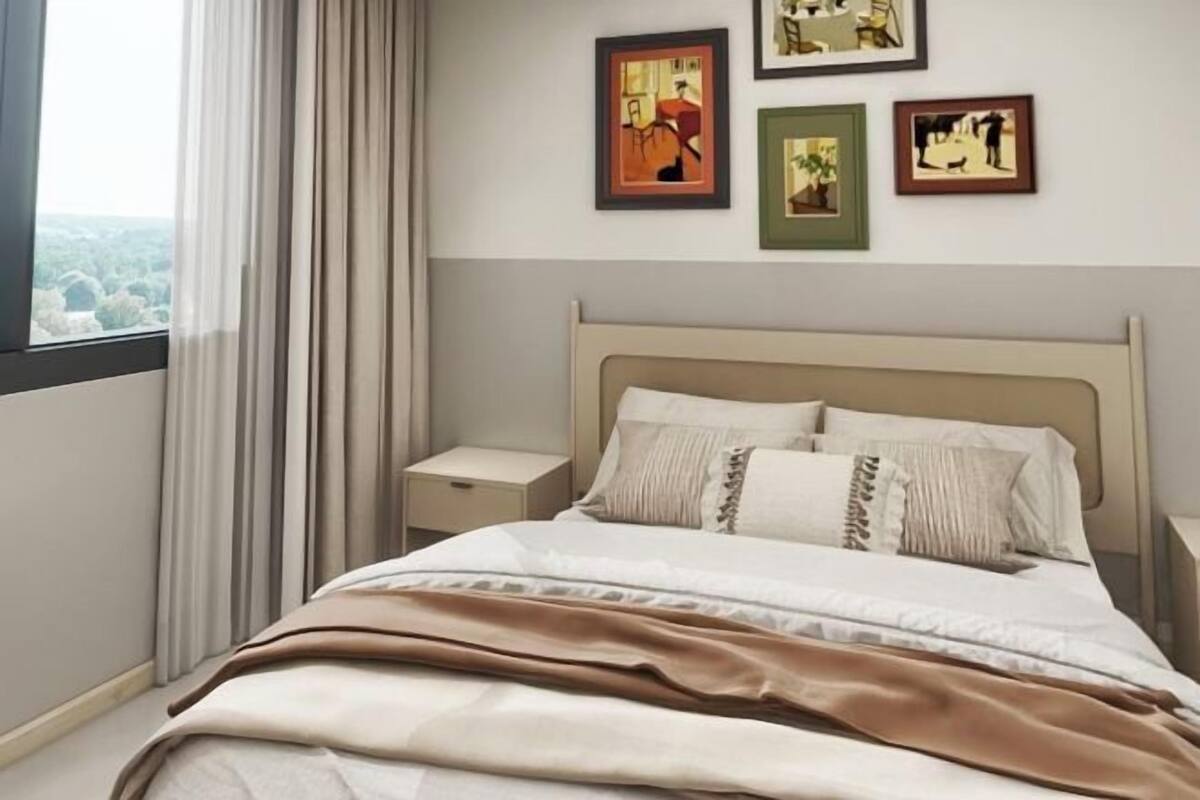 Una cama bien hecha con cabecera, mesita de noche y ventana con cortinas.