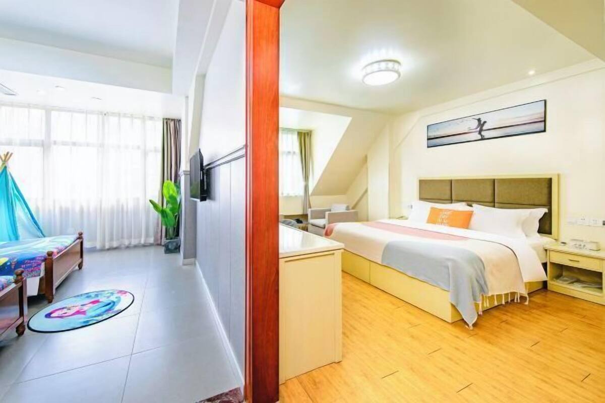 Una habitación de hotel con cama, mesita de noche y ventana con cortinas.
