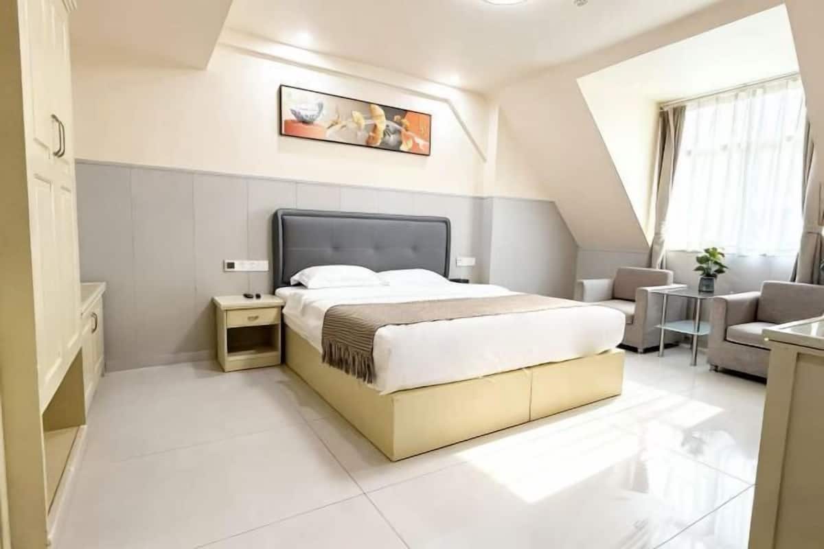 Una habitación de hotel moderna con una cama grande, mesitas de noche, un sofá y una pequeña mesa.
