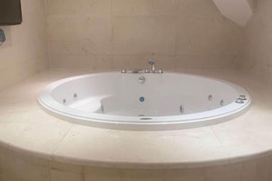 A round bathtub in a bathroom with tiled walls and a light-colored floor.